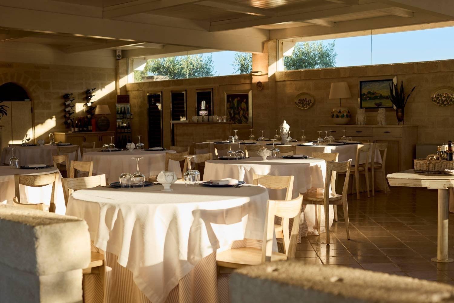 Sala interna con tavoli rotondi apparecchiati per un ricevimento in Valle d'Itria